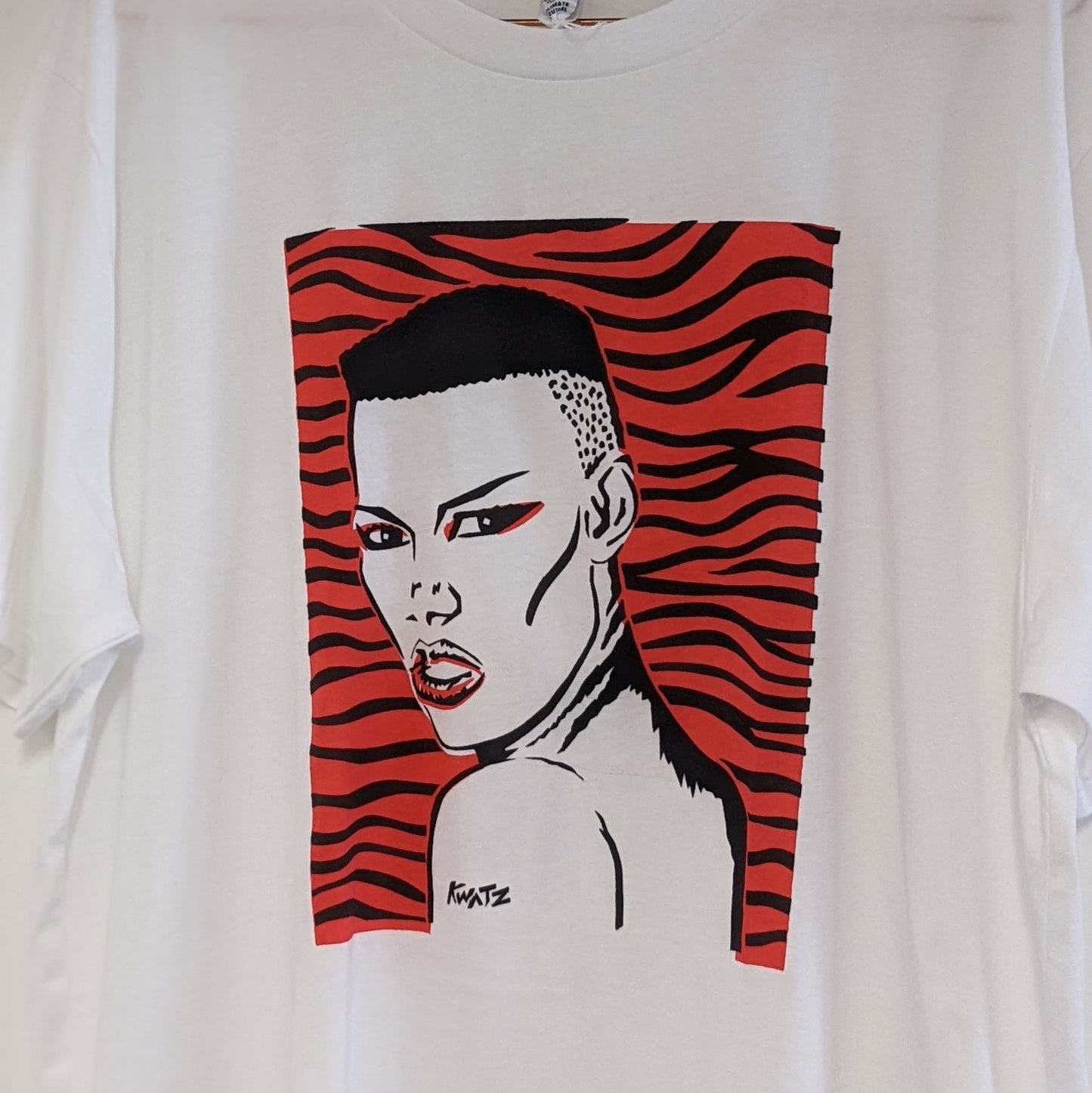 White T-shirt with a screenprinted design of Grace Jones predominantly red and black, set against a black background.
